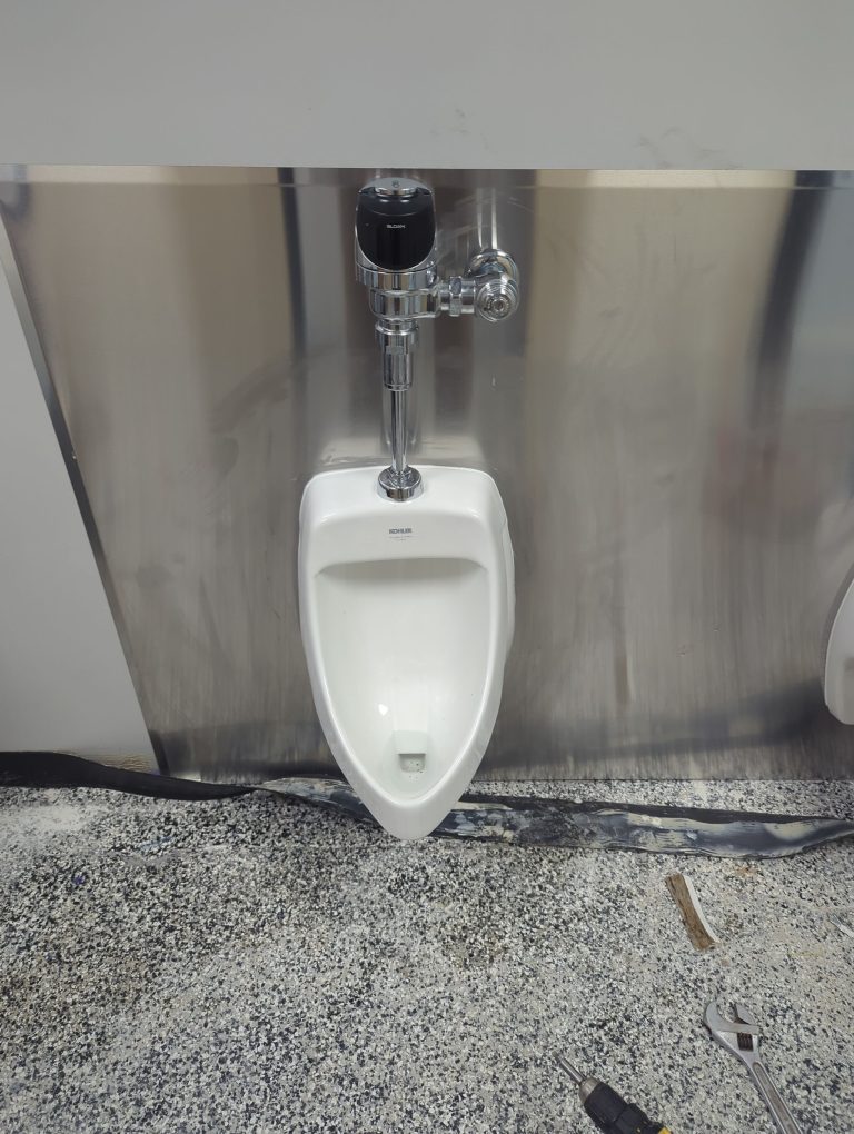 New urinal and flush valve installed in a commercial restroom
