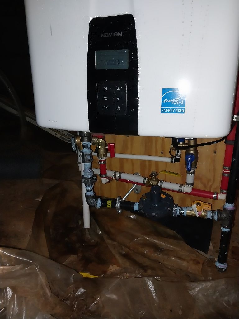 Wall-mounted tankless water heater installed by Custom Electric and Plumbing