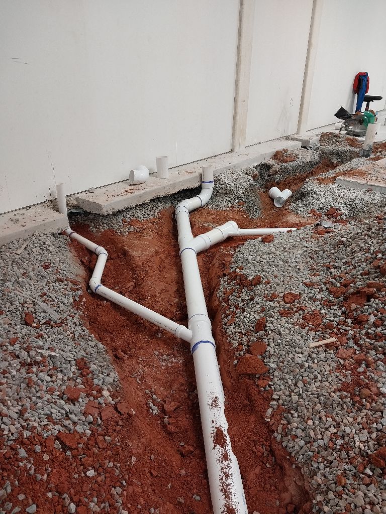 New PVC drain lines laid in a trench beside a house