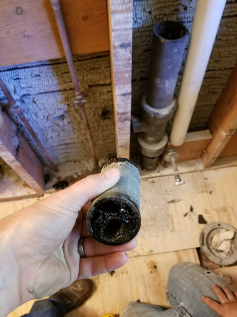 Section of old drain pipe cut out of a wall, clogged with buildup